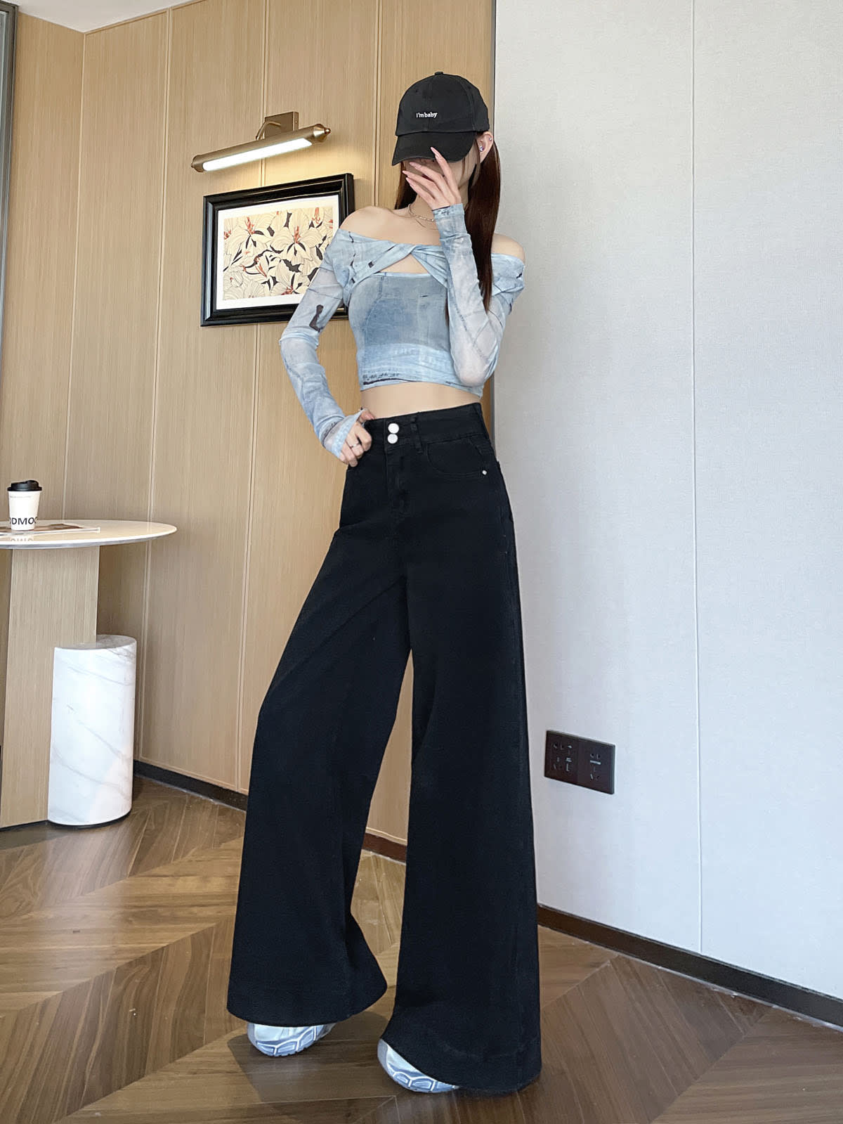 YEEYEEWang 솔리드 블랙 와이드레그 진, 아시안핏, 검은 캡, 전신 서기 포즈, 얼굴에 손, 우드 벽.