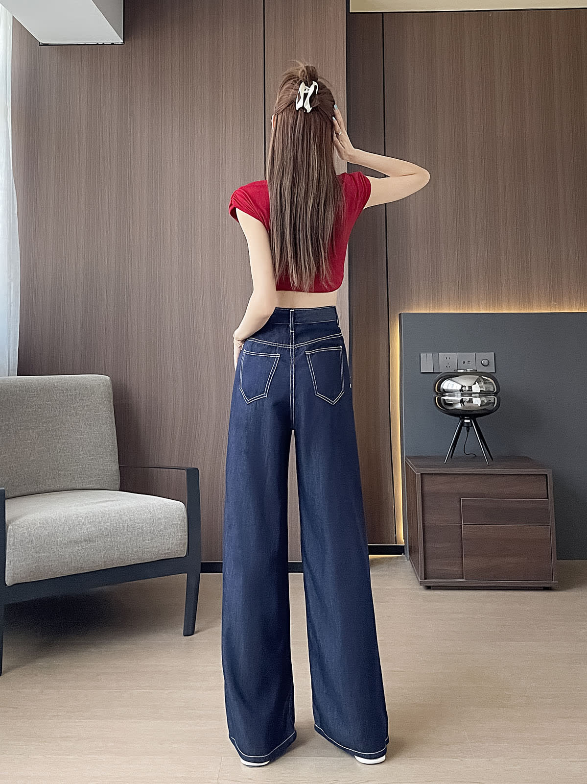 YEEYEEWang 데님 블루 와이드 레그 진, 아시안핏, 전신 뒷모습 선 자세, 한 손을 헤어 클립으로 올린 모습, 배색 스티치 더블 뒷면 패치 포켓.